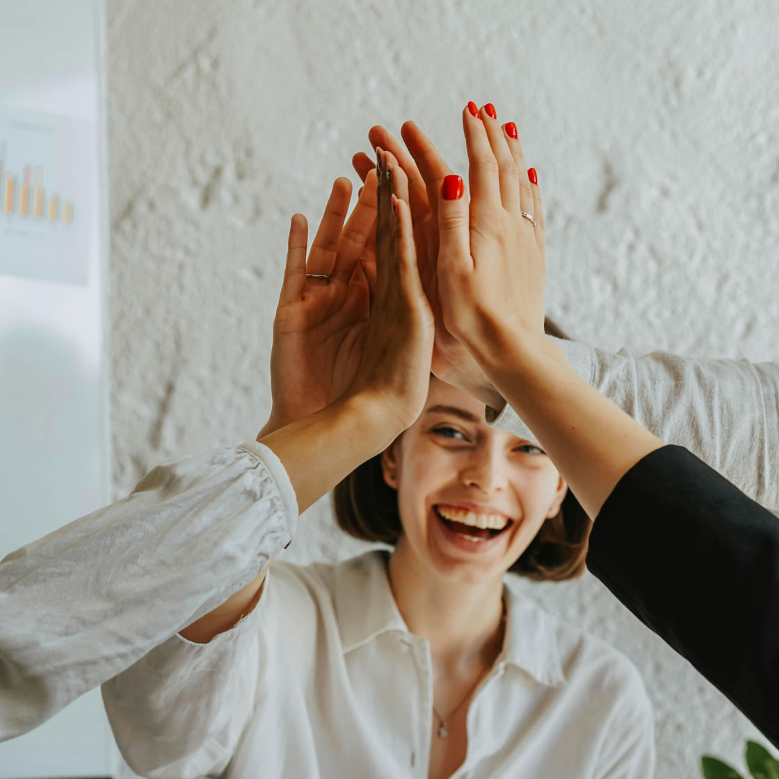 Happy colleagues high-fiving in a meeting, showcasing teamwork and success.