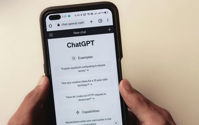 Close-up of hands holding a smartphone displaying the ChatGPT application interface on the screen.