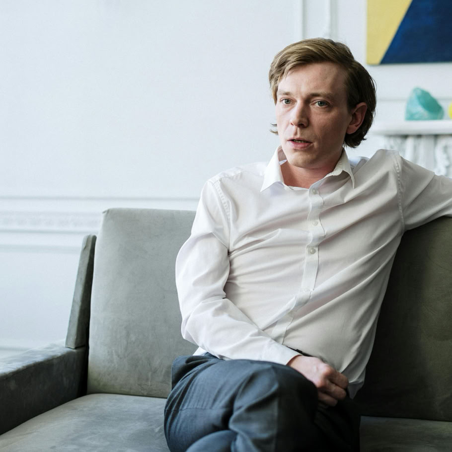 Confident man in white shirt sitting on sofa, representing consulting or therapy session indoors.